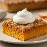 Slice of pumpkin dump cake topped with whipped cream.