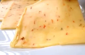 Close-up of sliced Pepper Jack Cheese with visible pepper bits.
