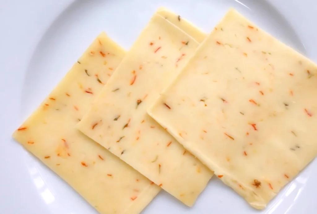 Close-up of sliced Pepper Jack Cheese with visible pepper bits.