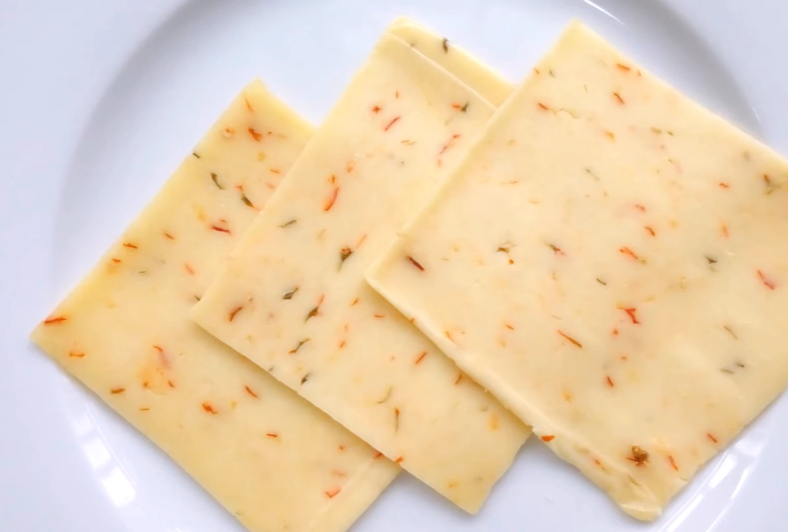 Close-up of sliced Pepper Jack Cheese with visible pepper bits.