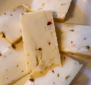 Close-up of sliced Pepper Jack Cheese with visible pepper bits.