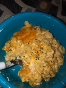 A creamy bowl of protein mac and cheese topped with fresh herbs.