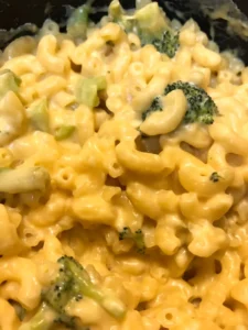 A creamy bowl of protein mac and cheese topped with fresh herbs.