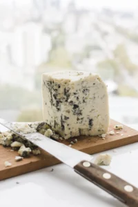 Close-up of blue cheese with visible blue veins and a creamy texture on a wooden board