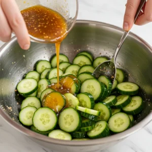 A bowl of Din Tai Fung cucumber salad, featuring crisp cucumber slices coated in a savory garlic-soy dressing with sesame seeds and chili oil.