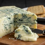 Close-up of creamy Gorgonzola cheese on a wooden board, with a cheese knife spreading its rich texture.