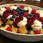 Blueberry French Toast baked in a white ceramic dish with golden top and bursting blueberries.