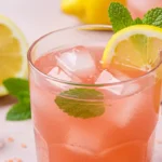 Pink salt weight loss drink in a glass with ice, lemon slice, and mint.