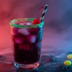 A glass of Drunk Witch cocktail with green sugar rim, cherry garnish, and purple drink over ice on a moody black marble surface.