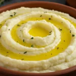 Creamy mashed potatoes swirled with melted butter and sprinkled with herbs in a rustic bowl