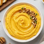 Pumpkin whipped feta dip in bowl with walnuts and thyme